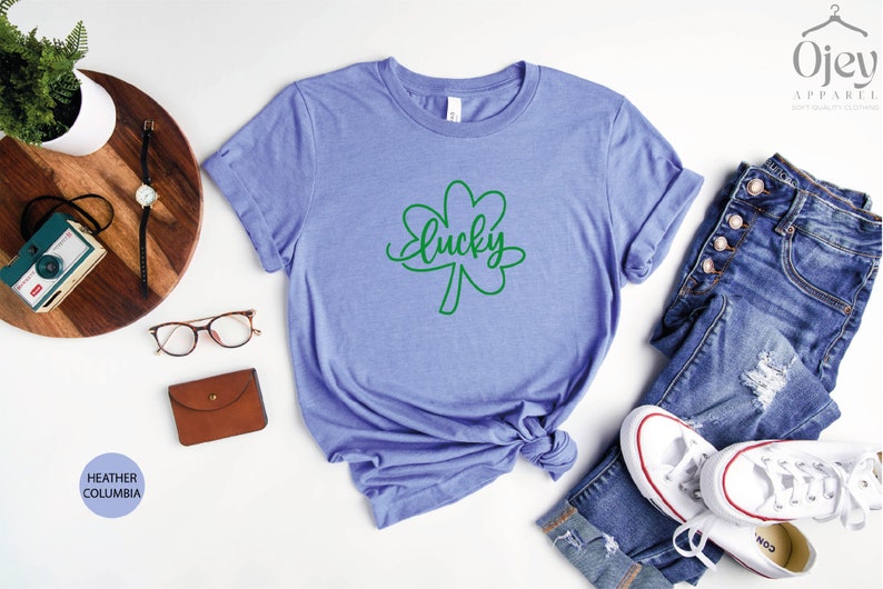 May include: A heather columbia blue t-shirt with a green shamrock and the word "lucky" written in cursive.