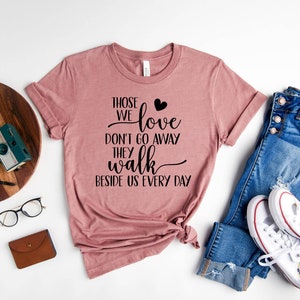 Peut inclure: Un t-shirt rose poussi&eacute;reux avec le texte "Those we love don't go away they walk beside us every day" en lettres noires avec un petit c&oelig;ur noir.