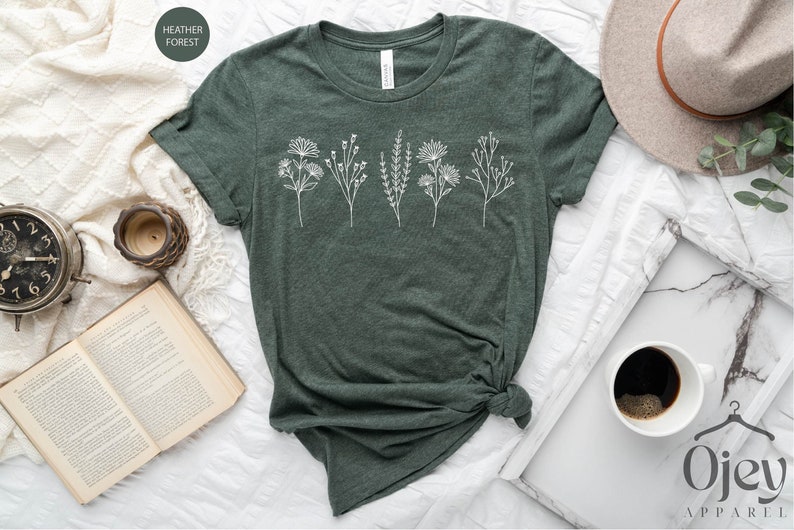 May include: A green t-shirt with a white floral design. The shirt is made of a soft, comfortable material and has a relaxed fit.