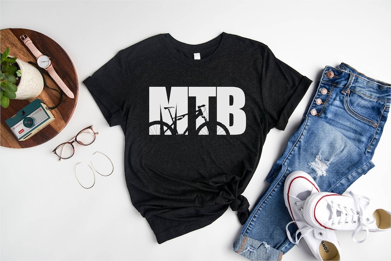 Puede incluir: Una camiseta negra con la palabra "MTB" en texto blanco. La "T" est&aacute; formada por la silueta de una bicicleta de monta&ntilde;a.