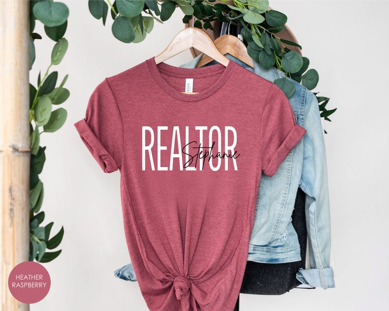 Peut inclure: T-shirt de couleur framboise heather avec le texte "REALTOR Stephanie" en lettres blanches et noires.