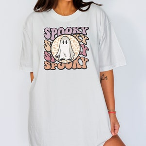 Puede incluir: Camiseta blanca de gran tama&ntilde;o con un gr&aacute;fico de un fantasma en un c&iacute;rculo con la palabra "Spooky" escrita en una fuente retro alrededor del c&iacute;rculo.