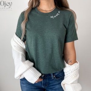 K&ouml;nnte beinhalten: Ein gr&uuml;nes T-Shirt mit dem Wort "mama" in wei&szlig;er Kursivschrift auf der Brust.