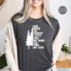 May include: Heather dark grey t-shirt with a white graphic of a pine tree and the text "AND INTO THE FOREST I GO TO LOSE MY MIND AND FIND MY SOUL".