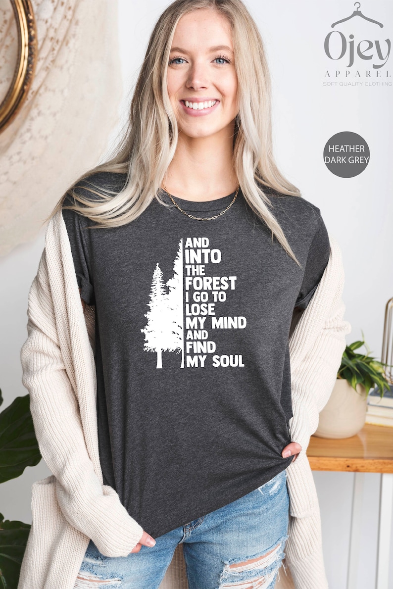 May include: Heather dark grey t-shirt with a white graphic of a pine tree and the text "AND INTO THE FOREST I GO TO LOSE MY MIND AND FIND MY SOUL".