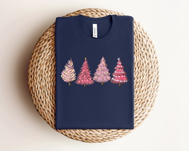 May include: A navy blue t-shirt featuring a design of four pink Christmas trees with gold lights and decorations.