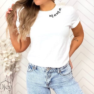 K&ouml;nnte beinhalten: Ein wei&szlig;es T-Shirt mit dem Wort "mama" in schwarzer Kursivschrift auf der Brust.