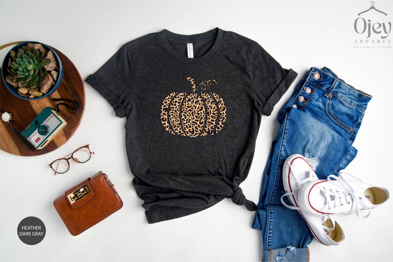 May include: A dark heather gray t-shirt with a leopard print pumpkin graphic and the text "Sister from another mother".