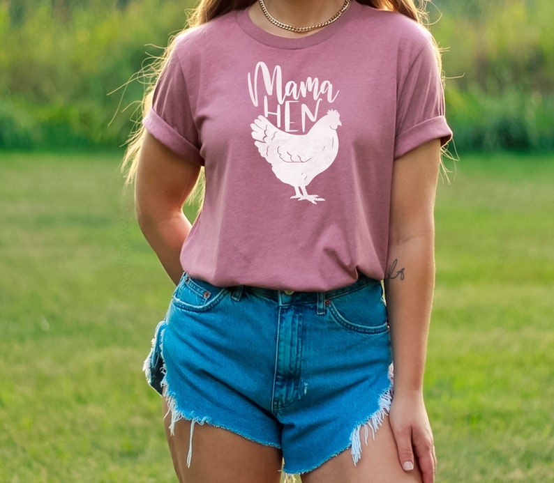 May include: A mauve t-shirt with a white graphic of a chicken and the text "Mama Hen".