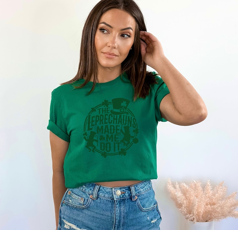 May include: A green t-shirt with a green circle graphic that says "The Leprechauns Made Me Do It". The graphic also includes a leprechaun with a hat and a pot of gold.