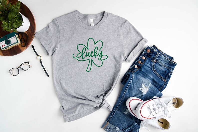 May include: A gray t-shirt with a green shamrock and the word "lucky" written in cursive.