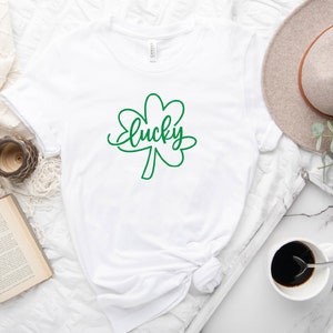 May include: White t-shirt with a green shamrock and the word "lucky" written in cursive.