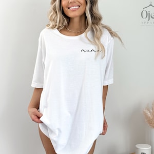 以下が含まれることがあります： 前面に黒い筆記体で「mama」と書かれた白いオーバーサイズのTシャツです。