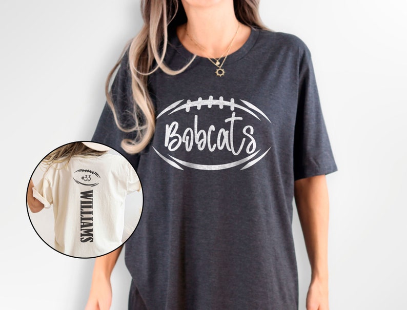 May include: A dark grey t-shirt with a white football graphic that says "Bobcats". A white t-shirt with a black football graphic and the text "#33 WILLIAMS" is shown in the background.
