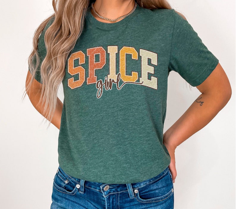 May include: A green t-shirt with the text "Spice girl" in a retro font with orange, yellow, and brown colors.