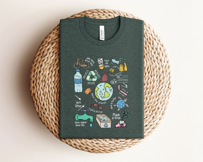 May include: A dark green t-shirt with a colorful illustration of ways to help save the planet. The illustration includes a bicycle, a water bottle, a recycling symbol, a globe, a turtle, a tree, and the words "Recycle, Reduce, Reuse, Save the Planet, Plant a Tree, Don't Litter, Save Water, Save Life".