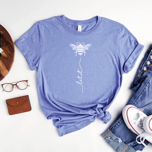 May include: A heather columbia blue t-shirt with a white bee graphic and the text "let it" printed on the front.