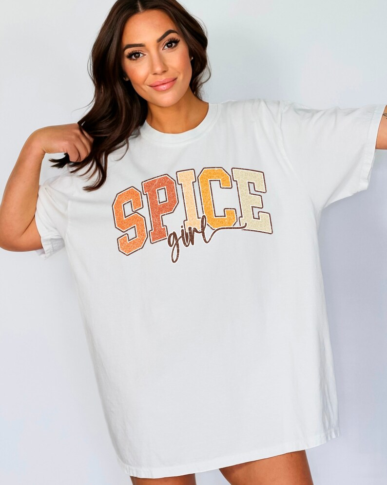 May include: White oversized t-shirt with a vintage-style graphic that says "SPICE girl" in orange, yellow, and brown.