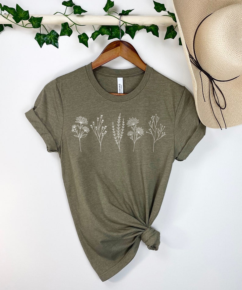 May include: A green t-shirt with a white floral design. The shirt is made of a soft, comfortable material and has a relaxed fit.