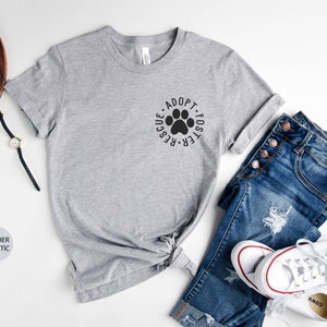 May include: A heather grey t-shirt with a paw print graphic and the text "Adopt Foster Rescue" in a circle around the paw print.