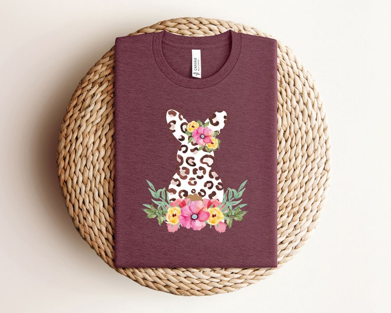 May include: A maroon t-shirt with a white and brown leopard print bunny silhouette with pink, yellow, and orange flowers.