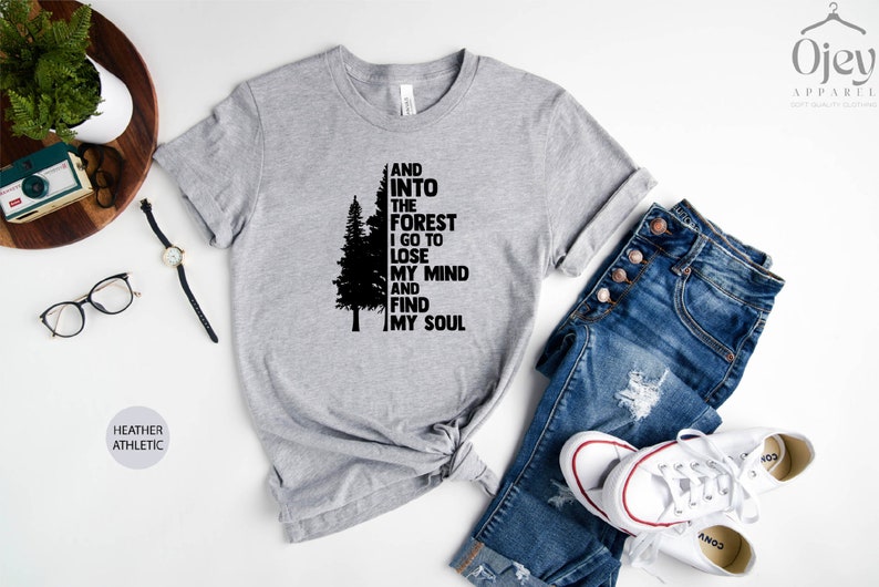 May include: A heather grey t-shirt with a black silhouette of a pine tree and the text "And into the forest I go to lose my mind and find my soul".