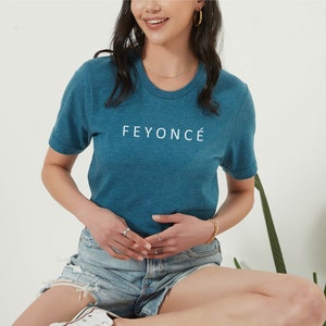 Pu&ograve; includere: Una maglietta blu turchese con la scritta "FEYONC&Eacute;" stampata in bianco sul davanti.