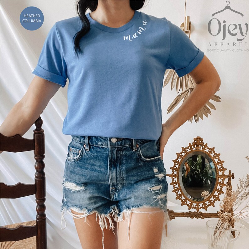 K&ouml;nnte beinhalten: Ein hellblaues T-Shirt mit dem Wort "mama" auf der Vorderseite gestickt. Das Shirt wird von einer Person mit Jeans-Shorts getragen.
