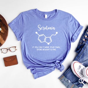 May include: A purple t-shirt with a white graphic of the chemical structure of serotonin and the text "Serotonin. If you can't make your own, store bought is fine."