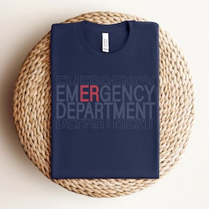 Może przedstawiać: Koszulka w kolorze granatowym z nadrukiem "EMERGENCY DEPARTMENT" w kolorze białym, z wyr&oacute;żnionym słowem "ER" w kolorze czerwonym.