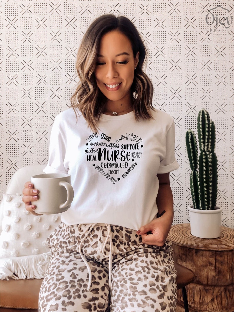 May include: White t-shirt with a black heart graphic that says "strong care tough & kind nurture selfless support skilled NURSE heal committed heart encourage compassion".