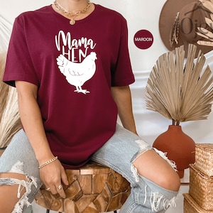 May include: A maroon t-shirt with a white graphic of a chicken and the text "Mama Hen".