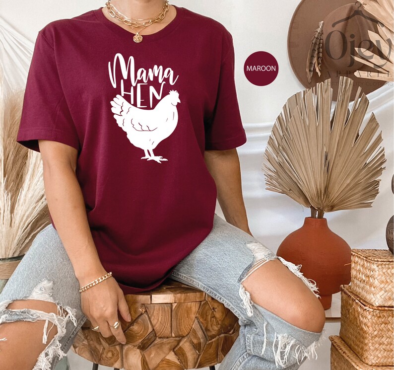 May include: A maroon t-shirt with a white graphic of a chicken and the text "Mama Hen".