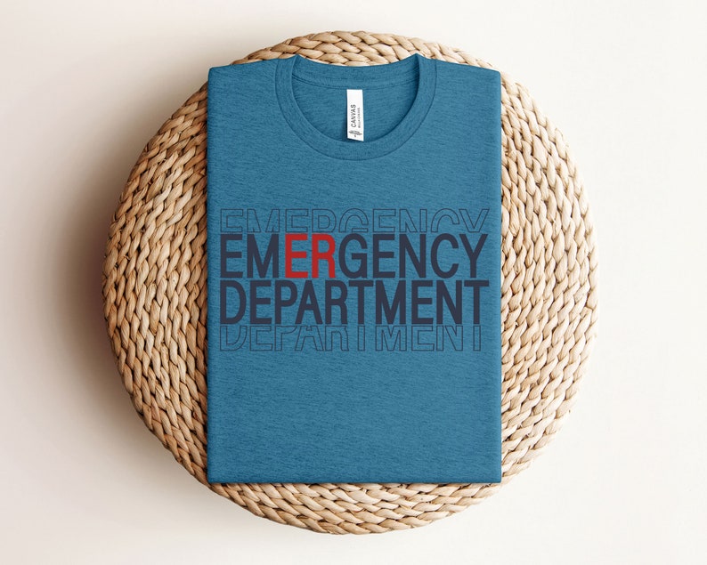 Może przedstawiać: Niebieska koszulka z nadrukiem "EMERGENCY DEPARTMENT" w kolorze czarnym i czerwonym. Tekst jest ułożony jeden nad drugim, a "ER" jest czerwone.