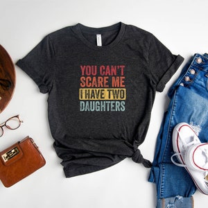 Puede incluir: Camiseta gris oscuro jaspeada con un gr&aacute;fico de estilo vintage que dice "You can't scare me I have two daughters".