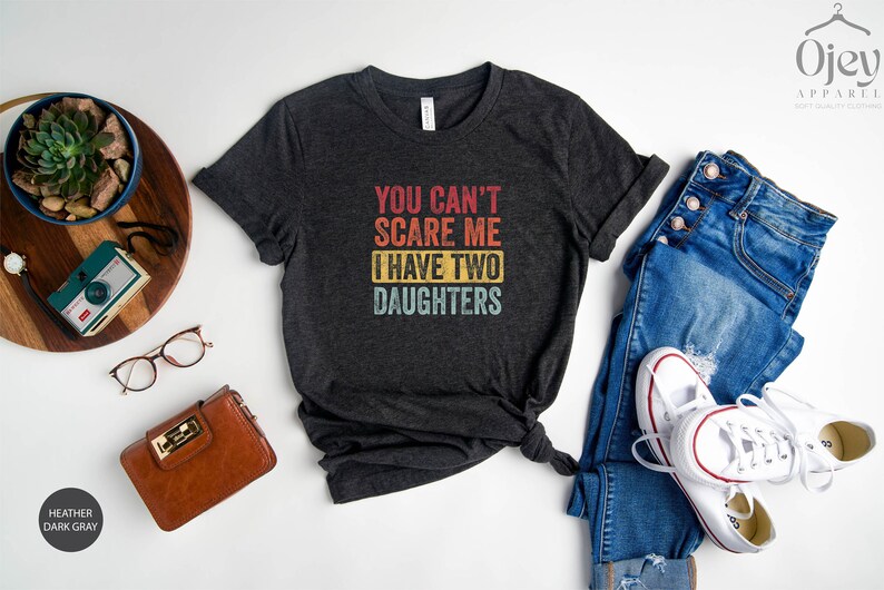 Puede incluir: Camiseta gris oscuro jaspeada con un gr&aacute;fico de estilo vintage que dice "You can't scare me I have two daughters".
