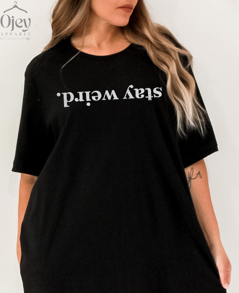 May include: Black oversized t-shirt with the text "Stay Weird." printed in white.