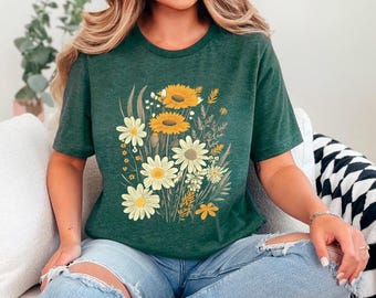 May include: A green t-shirt with a floral print featuring yellow and white daisies. The daisies are arranged in a bouquet with green leaves and stems.