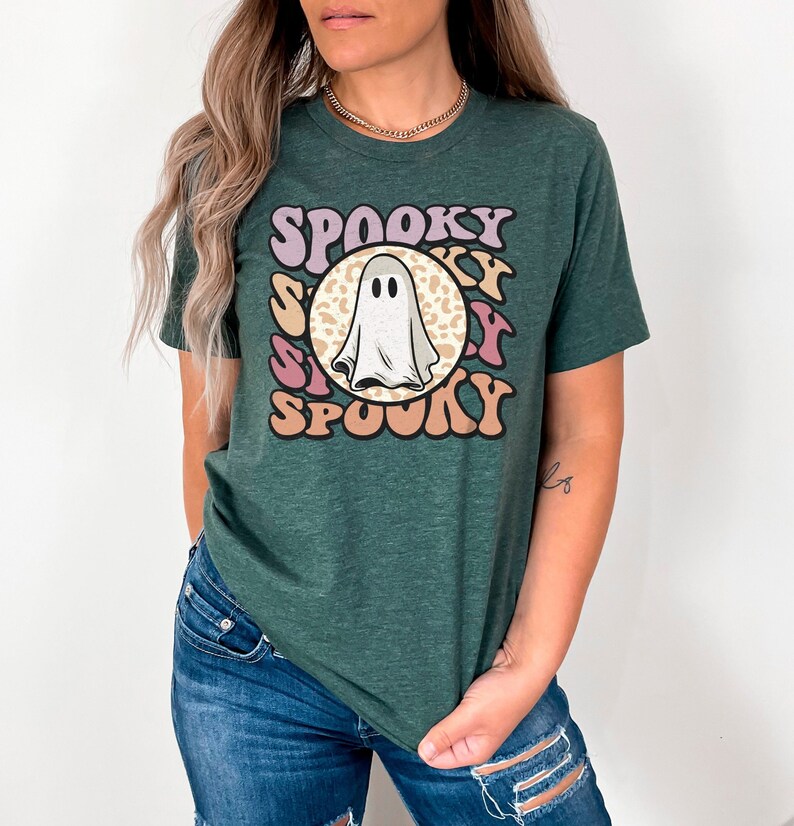Puede incluir: Una camiseta verde con un gr&aacute;fico retro de un fantasma en un c&iacute;rculo con la palabra "SPOOKY" repetida a su alrededor.