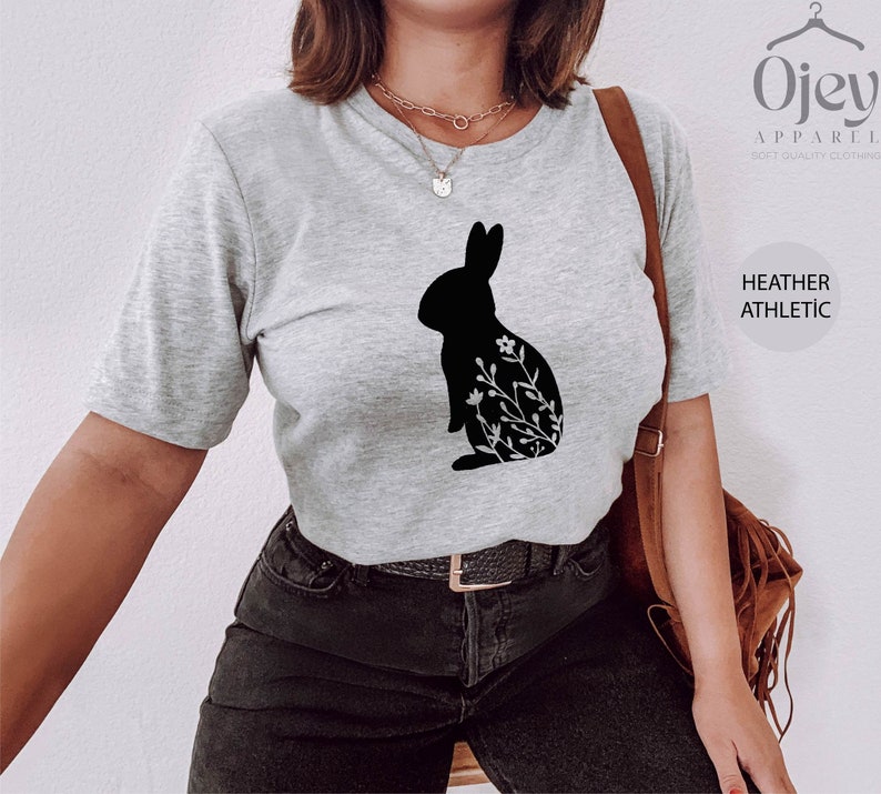 May include: A heather gray t-shirt with a black silhouette of a rabbit with floral details. The text "Ojev Apparel Soft Quality Clothing" and "Heather Athletic" are visible on the right side of the image.
