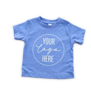 May include: A light blue short-sleeved t-shirt with a white circle and the text "YOUR LOGO HERE" in a handwritten font.