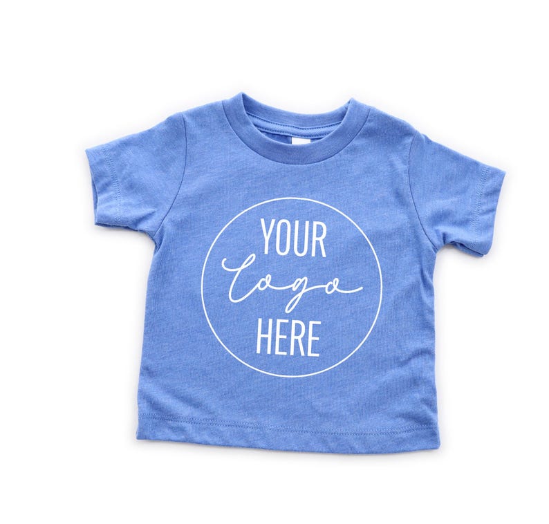 May include: A light blue short-sleeved t-shirt with a white circle and the text "YOUR LOGO HERE" in a handwritten font.