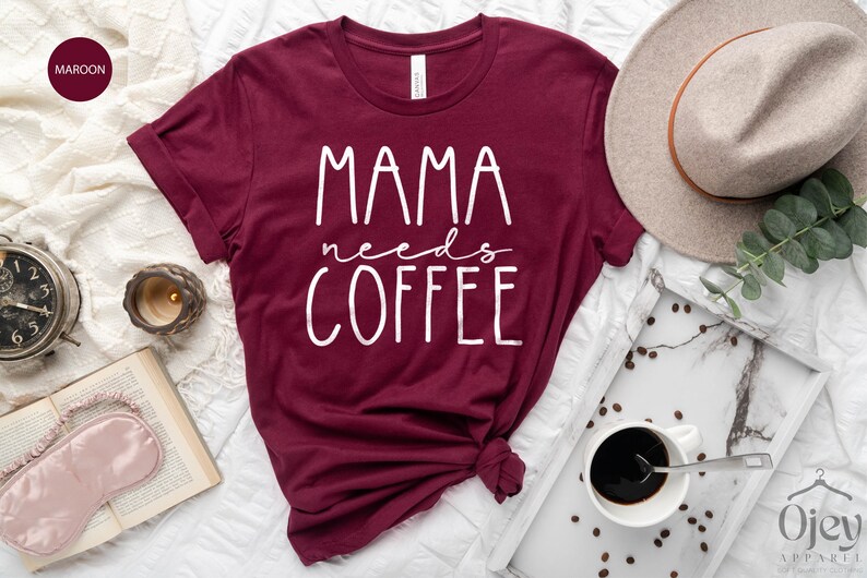 May include: A maroon t-shirt with the text "MAMA needs COFFEE" in white lettering.