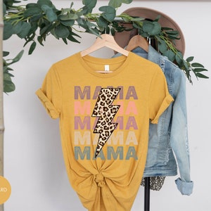 Op de afbeelding: Een mosterdgeel T-shirt met een bliksemgraphic in luipaardprint en de tekst "MAMA" die in verschillende kleuren wordt herhaald.