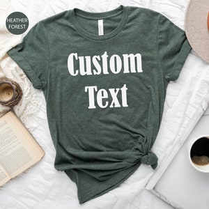 May include: A dark green t-shirt with the text "Custom Text" printed in white on the front.