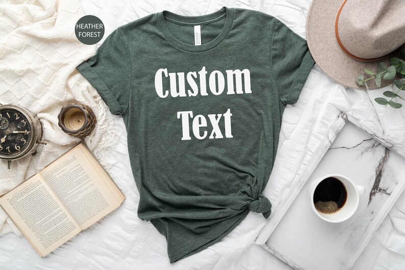 May include: A dark green t-shirt with the text "Custom Text" printed in white on the front.