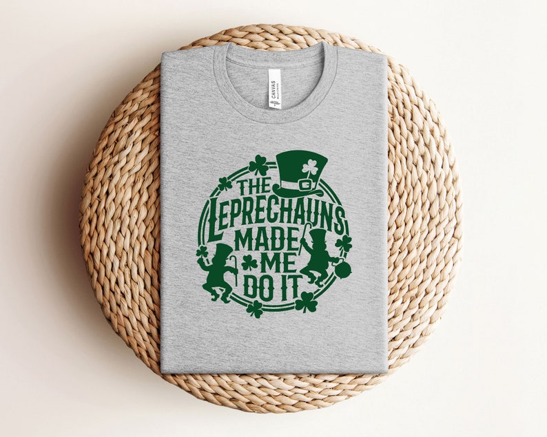 May include: A gray t-shirt with a green graphic that says "The Leprechauns Made Me Do It". The graphic features a leprechaun with a hat and a pot of gold.
