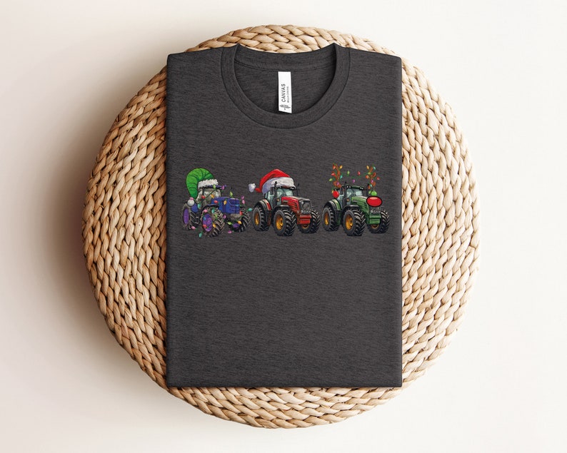 Peut inclure: Un t-shirt gris fonc&eacute; avec un motif de trois tracteurs d&eacute;cor&eacute;s pour No&euml;l. Les tracteurs sont vert, bleu et rouge. Les tracteurs portent des chapeaux de P&egrave;re No&euml;l et ont des lumi&egrave;res de No&euml;l.