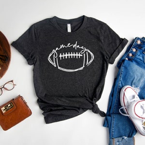 Peut inclure: Un t-shirt gris fonc&eacute; chin&eacute; avec un graphique blanc d'un ballon de football et le texte "game day".