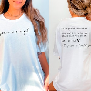 May include: White t-shirt with the text "you are enough" printed on the front and "Dear person behind me: The world is a better place with you in it. Lots of love, - the person in front of you" printed on the back.